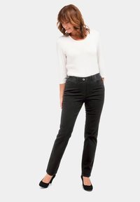 Pantalon en denim noir avec une coupe ajustée, des coutures discrètes et une fermeture à bouton classique, associé à un haut à manches trois-quarts blanc.