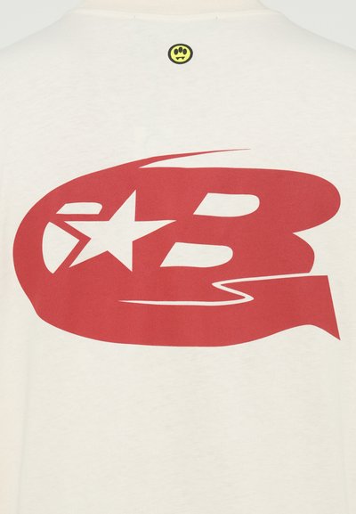 T-shirt color crema con una grande grafica rossa raffigurante la lettera "B" e una stella. Piccolo logo giallo sulla nuca del retro. Tessuto morbido.