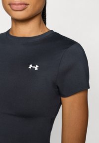 Black fitted athletic t-shirt made of smooth fabric, featuring short sleeves and a small white Under Armour logo on the chest.