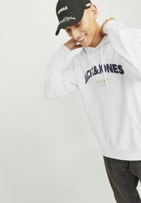 Grauer Hoodie mit einem Logo in Marineblau; besitzt eine Fronttasche und Kordelzug. Schwarze Kappe mit weißem Text; flaches Schirmdesign.