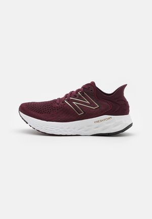 Weinroter New Balance Laufschuh mit gestricktem Obermaterial, weißer, gepolsterter Sohle mit der Aufschrift Fresh Foam und metallischem Logo an der Seite.