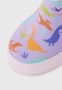 Baskets imperméables à motif dinosaure en lavande, avec des illustrations colorées de divers dinosaures et empreintes, et une semelle texturée rose.
