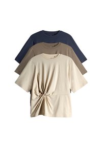 Three short-sleeve t-shirts in beige, taupe, and navy. The beige shirt features a knotted detail at the waist, all made of soft fabric.