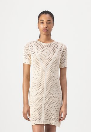 Knit dress in cream with diamond pattern, short sleeves, and a round neckline; textured, open weave design.
