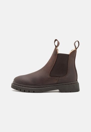 Brown leather Chelsea boot with elastic side panels, pull tabs, and a chunky rubber sole featuring deep grooves for traction.