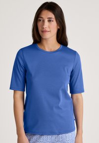 Blauwe t-shirt met korte mouwen, gemaakt van zachte stof, met een ronde halslijn en een gladde textuur, gecombineerd met een patroonrok of -broek.