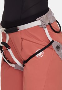 Różowe spodenki do wspinaczki z czarnym paskiem, białymi szelkami i zamkiem błyskawicznym w kieszeni. Logo z boku oraz regulowany sprzęt zapewniający bezpieczne dopasowanie.