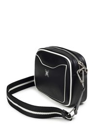 Svart läder crossbody-väska med vit kantning, dragkedjestängning och avtagbart bälte med svart och vitt randigt mönster.