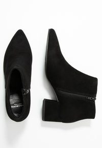 Czarne zamszowe botki za kostkę z szpiczastym noskiem i niskim blokowym obcasem. Posiadają boczny zamek błyskawiczny i gładką fakturę.