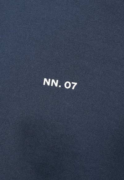 Dunkelblauer Stoff mit weißem Text "NN. 07", der in der Mitte gedruckt ist und ein strukturiertes Strickmaterial zeigt.