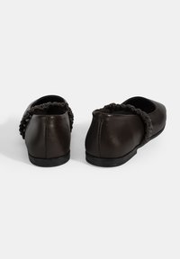 Schwarze Leder-Ballerinas mit runder Schuhspitze, die an der Ferse geraffte Akzente und eine flache, flexible Sohle aufweisen.
