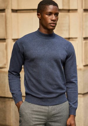 Mørkeblå, langærmet strikketrøje med ribbet mock neck og manchetter, der har en glat tekstur og tætsiddende design.