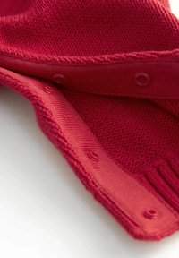 Tejido de punto rojo con costuras texturizadas, que presenta una fila de botones de presión a juego a lo largo del borde para el cierre.