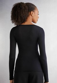 Schwarzes Langarmshirt mit einer taillierten Passform, Rundhalsausschnitt und glattem Stoff, von hinten gesehen, ohne sichtbare Grafiken oder Verzierungen.