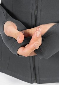 Dunkelgraue Zip-Jacke mit Daumenlöchern in den Ärmeln, die eine glatte Textur und eine eng anliegende Passform aufweist, hervorgehoben durch detaillierte Nähte.