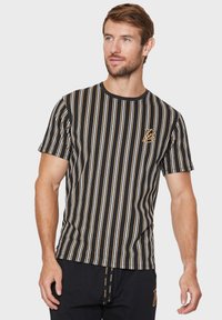 Sort-hvid stribet t-shirt med korte ærmer og guldaccentlogo på brystet samt rund halsudskæring. Blødt bomuldsmateriale med en afslappet pasform.