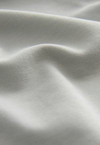 Tissu gris clair avec une surface lisse et légèrement texturée. Affiche de douces plis et un éclat subtil. Convient pour diverses applications textiles.