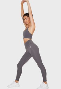 Set di reggiseno sportivo grigio e leggings a vita alta, caratterizzato da un tessuto elastico, design senza cuciture e un piccolo logo sul petto.