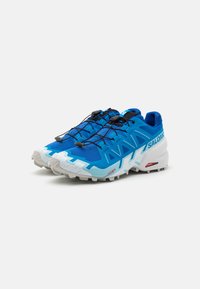 Des chaussures de course bleues avec une tige en mesh léger, des accents texturés et une semelle blanche robuste. Elles disposent d'un système de laçage sécurisé.