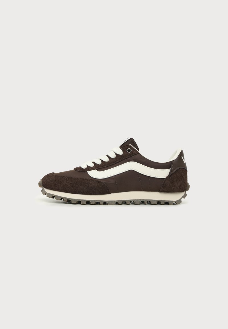 Σκούρο καφέ sneaker χαμηλής κοπής με λευκή πλαϊνή ρίγα, λευκά κορδόνια και υφή στη σόλα σε ανοιχτό φόντο.