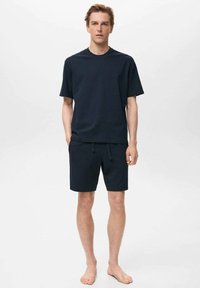 Navyblaues Baumwoll-T-Shirt mit kurzen Ärmeln, kombiniert mit passenden Shorts, die einen elastischen Bund und eine Kordel haben. Glatte Textur, lässige Passform.