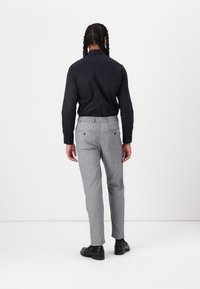 Svart långärmad skjorta och grå strukturerade byxor. Byxorna har ett elastiskt midjeband och två bakfickor. Slätt tyg och figurnära design.