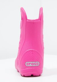 Botte rose imperméable en matériau semblable au caoutchouc, dotée d'une surface texturée, d'un talon arrondi et d'une étiquette logotée à l'arrière.