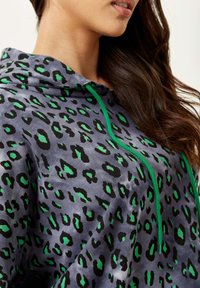 Hooded sweatshirt in gray with black and green leopard print. Features a drawstring neckline and a soft texture.