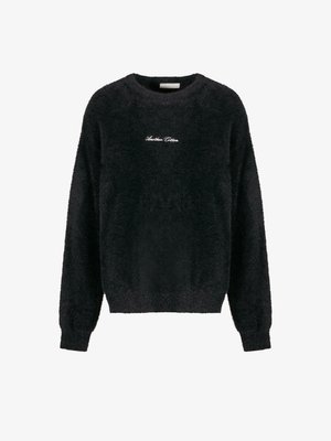 Fekete bolyhos pulóver, kerek nyakkivágással, hosszú ujjal és rövid fazonnal. Fehér hímzett szöveget tartalmaz a mellkasán. Puha tapintású.