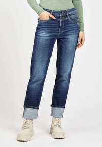 Dark blue denim jeans with a straight-leg cut, rolled cuffs, and two-button waistband. Features visible stitching and back pockets.