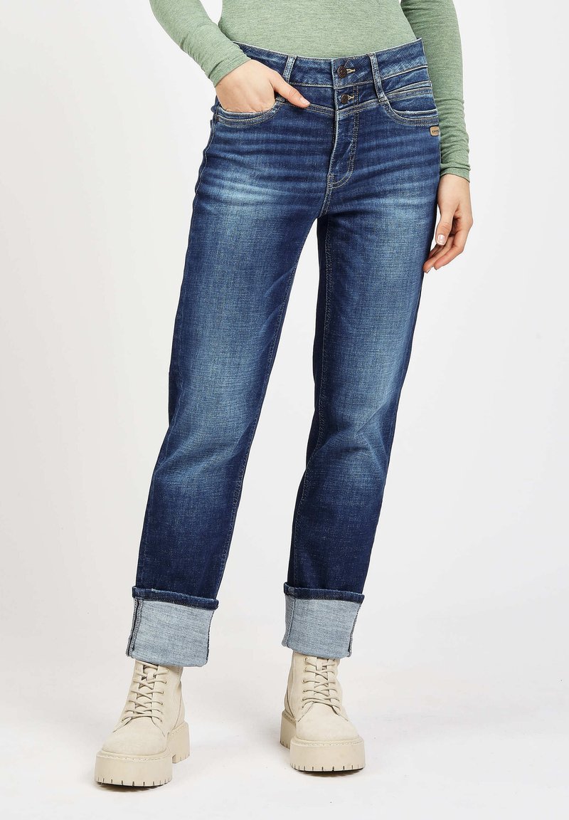 Dark blue denim jeans with a straight-leg cut, rolled cuffs, and two-button waistband. Features visible stitching and back pockets.