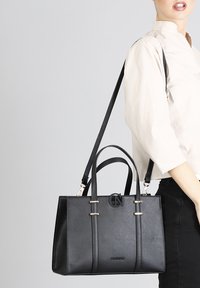 Bolso estructurado negro hecho de material sintético texturizado. Cuenta con dos asas, una correa de hombro ajustable y detalles en metal.