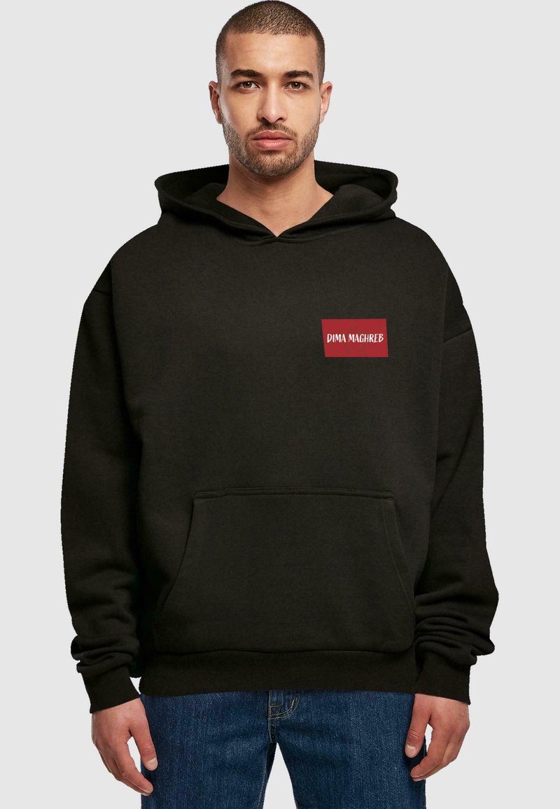 Melns kapucis, izgatavots no mīksta auduma, ar priekšējo kabatu, lielu kapuci un sarkanu taisnstūra formas logo uzšuvumu ar uzrakstu "DIMA MAGHREB".