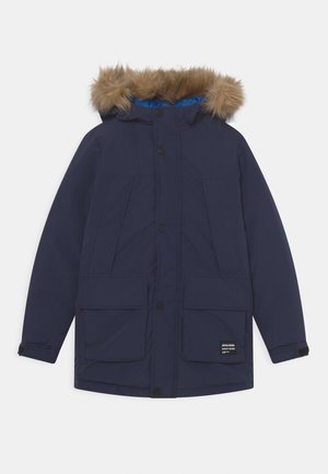 Parka d'hiver bleu marine avec capuche bordée de fourrure, fermeture à boutons sur le devant, plusieurs poches avant et sangles réglables aux poignets.