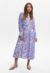 Robe longue à boutons en tissu transparent avec un motif floral rose et bleu. Elle a une coupe décontractée, des manches longues et une longueur midi.
