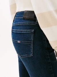 Tamno plave traperice s leđnim džepom na kojem se nalazi mala oznaka i kontrastnom šavom. Slim fit kroj s srednjim strukom.