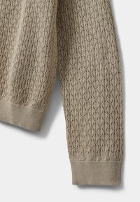 Gai krēms adīts džemperis ar dimantu raksta tekstūru, ribotām piedurknēm un apakšmalu. Pieejams mīksta, elpojoša materiāla.