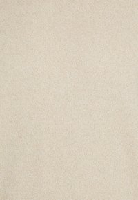 Tissu en tricot beige avec une texture douce, présentant un motif uniforme et une légère variation de ton sur toute la surface.