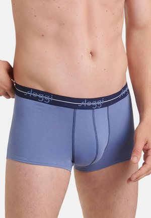 Männlicher Oberkörper trägt blaue Sloggi Boxershorts mit dunkelblauem Bund und Logo, Hand richtet den Bund auf der linken Seite.