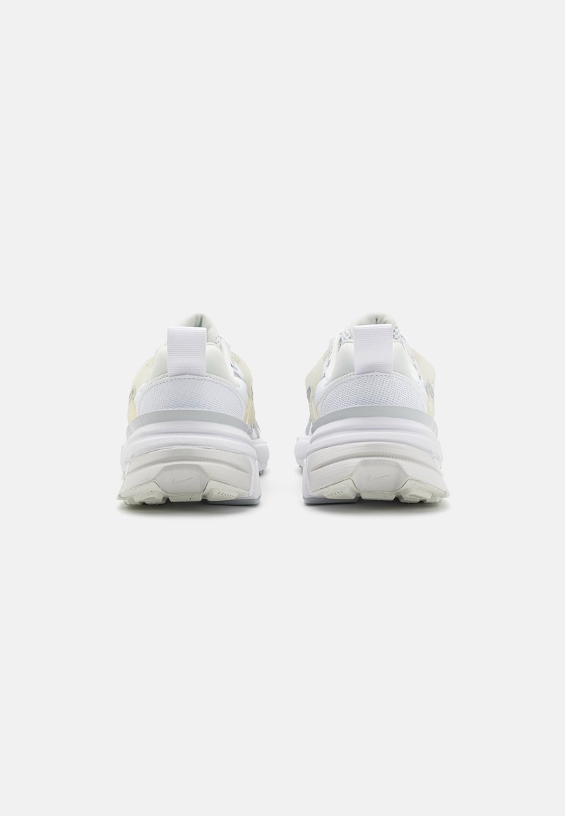 Scarpe da ginnastica bianche con upper in mesh e suola in gomma, caratterizzate da una forma curva, un'ammortizzazione del tallone prominente e un design minimalista.