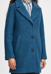 Teal wolblend jas met een textuurfinish, geknipte revers, drie zwarte knopen en zijzakken. Tailored fit met lange mouwen.
