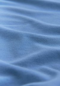 Puha, kék textil, sima, enyhén texturált felülettel, látható finom bordázattal és gyengéd hullámokkal. Ideális alkalmi ruházathoz.
