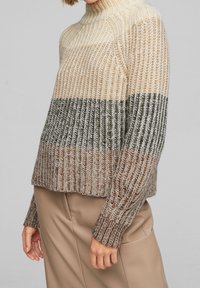 Maglione a righe crema, beige e oliva in maglia, con collo alto e texture a coste. Vestibilità ampia, maniche lunghe e orlo corto.