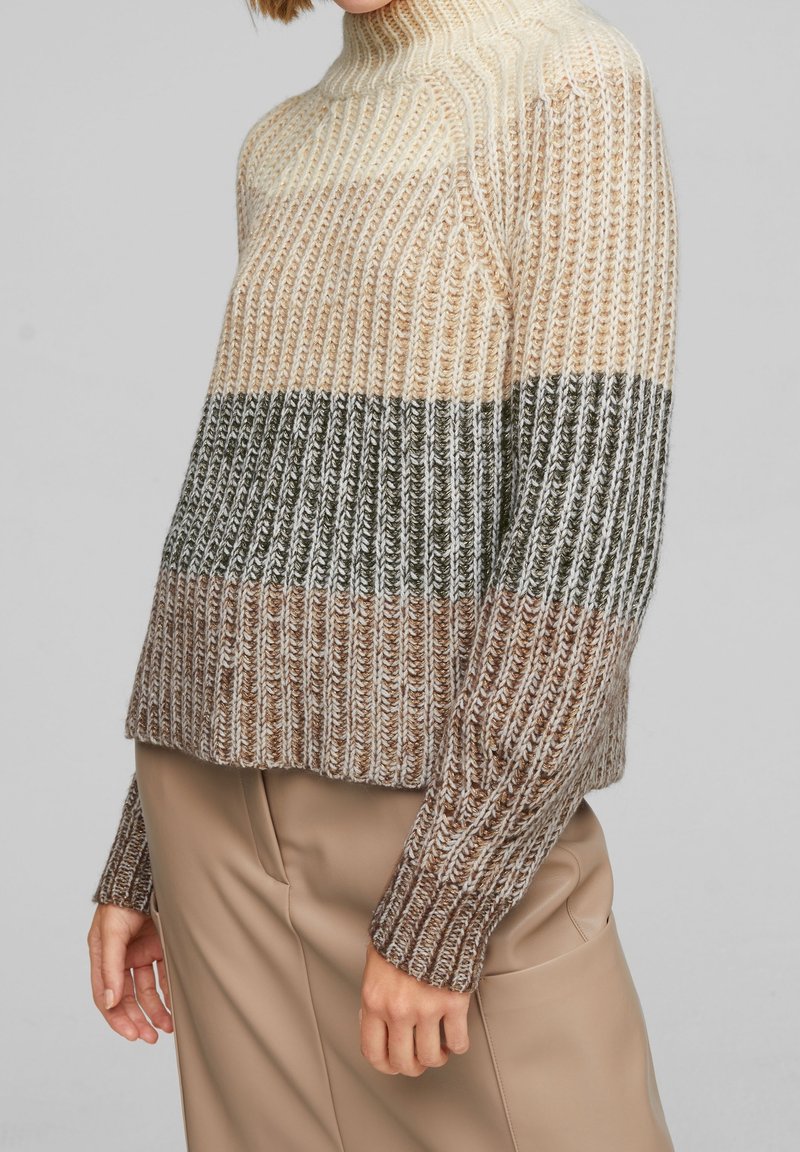 Maglione a righe crema, beige e oliva in maglia, con collo alto e texture a coste. Vestibilità ampia, maniche lunghe e orlo corto.