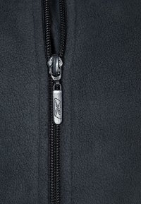 Svart fleecetyg med en silverfärgad metalldragkedja som är delvis stängd, vilket visar ihopkopplade dragkedjestänger och en rektangulär dragtab.