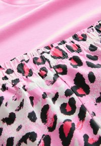 Rosa träningslinne med en strukturväv, med en elastisk midja prydd med ett mönster av rosa och svarta leopardfläckar.