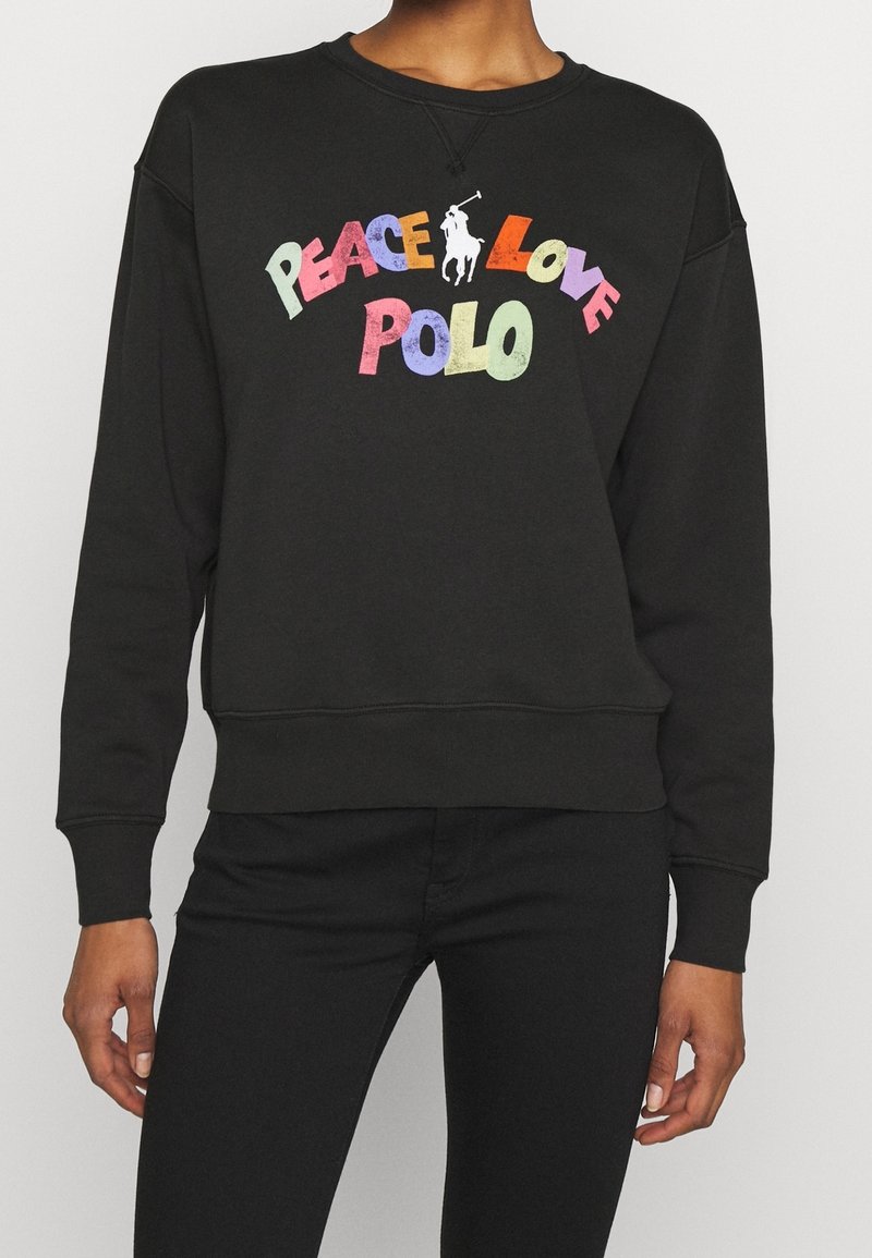 Zwarte trui van katoen, met een ronde hals en de grafische tekst "PEACE LOVE POLO" in kleurrijke letters. Geribbelde manchetten en zoom.