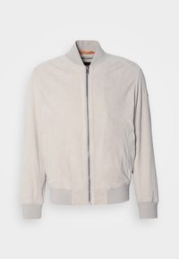 Veste bomber beige clair avec fermeture éclair à l’avant, poignets, col et ourlet côtelés, présentée sur fond blanc.