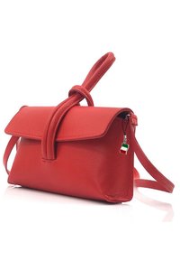 Sac à main en cuir rouge avec un détail en nœud sur la sangle, fermeture à rabat et une étiquette ressemblant à un drapeau italien. Texture lisse et forme structurée.
