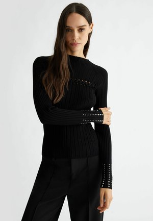 Maglione nero a coste con maniche lunghe, caratterizzato da dettagli a taglio sul petto e applicazioni di borchie sui polsini.